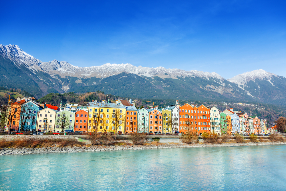 An image of the roofs of Innsbruck with mountains on a background and Christmas lights on a foreground at evening - Innsbruck landscape